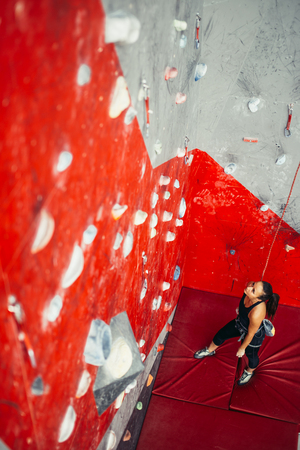 High angle view of woman practicing wall climbing on a campus board. Woman climbing on a campus board at a wall climbing gym.の写真素材