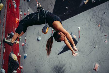 Active happy woman overhanging on tightrope in the training climbing centerの写真素材
