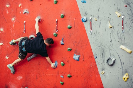 Man on artificial exercise climbing wallの写真素材