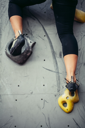 Bottom close up view of rock climber female feet on artificial climbing wall.の写真素材