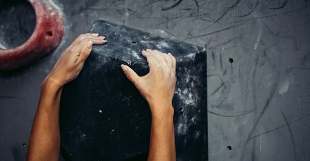 Female climber hands holding artificial boulder in climbing gym, closeup shotの写真素材