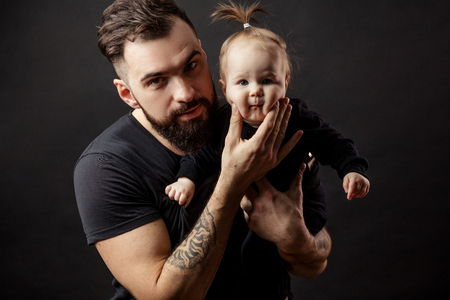 Young athletic father with adorable baby on black backgroundの写真素材