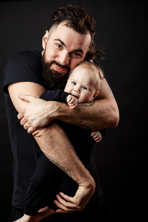 Young athletic father with adorable baby on black backgroundの写真素材
