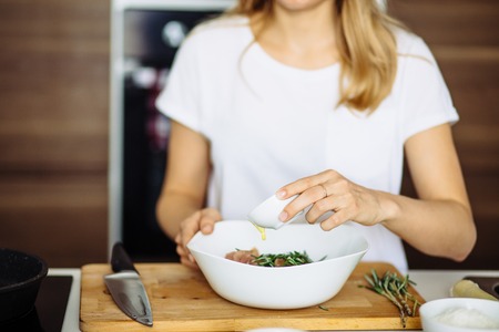 Cropped view of woman hands cutting beef on cutting board.の写真素材