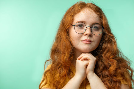 Studio shot of ginger young woman with loose hair looking at camera at studio