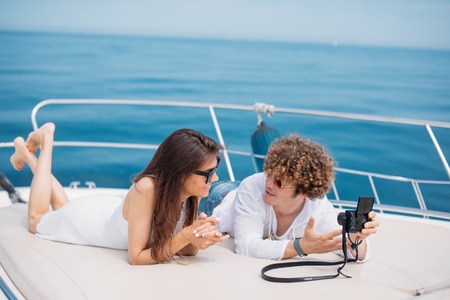 Attractive couple on the yacht. Young man is taking photo of his girlfriendの写真素材