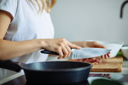 Cropped view of woman hands cutting beef on cutting board.の写真素材