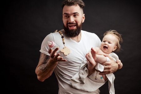 Father holding and taking care of little infant baby, feeding from bottle.