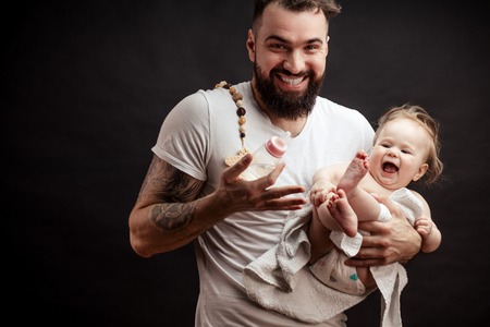 Father holding and taking care of little infant baby, feeding from bottle.の写真素材