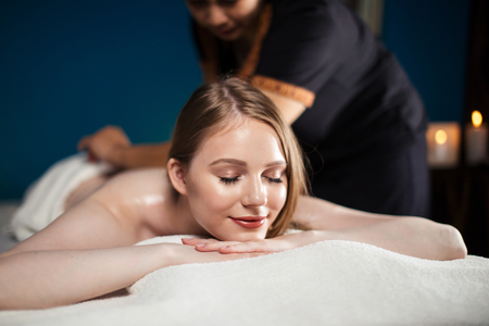 Woman receives body massage at spa salonの写真素材