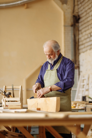 old shop teacher showing how use plane while working with timberの写真素材