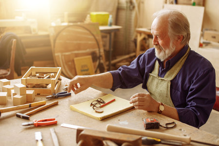 old handsome man is going to take hammer while working in the repair shop