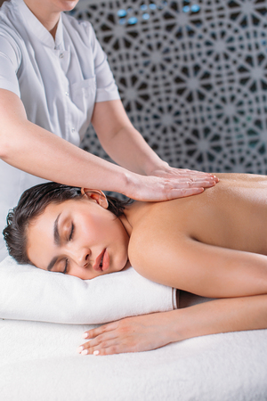 female doing the massage to nude pleasant woman with closed eyesの写真素材