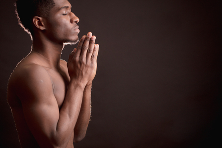 profile of nacked black male holding palms together is worshiping Godの写真素材