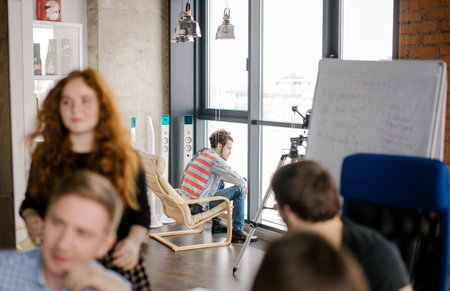 resentful guy in stylish clothes is sitting on the armchair far from his friends