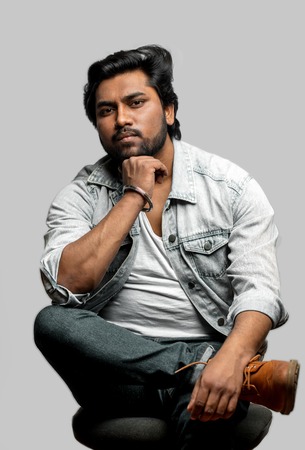 indian guy sitting with pensive lookの写真素材