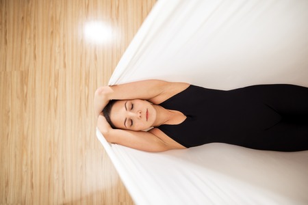 top view photo. fit girl is lying on the whit hammock on the floorの写真素材