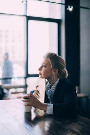 good-looking blond girl is leaning on her tablet and thinking about future plansの写真素材