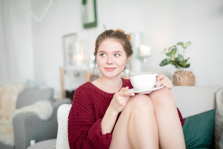 beautiful woman with blue eyes sitting on the sofa with pensive lookの写真素材