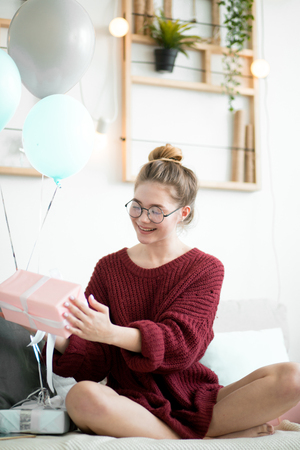 cheerful charming girl holding the present indoorsの写真素材