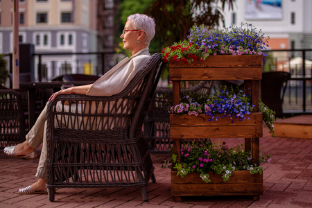 lonely wwoman is sitting in the armchair at the cafe with beautiful flowersの写真素材