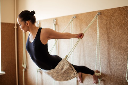 young woman is performing the yoga exercise on the ropesの写真素材