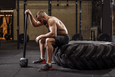 handsome bodybuilder with closed eyes is resting after sledgehammer exercisesの写真素材