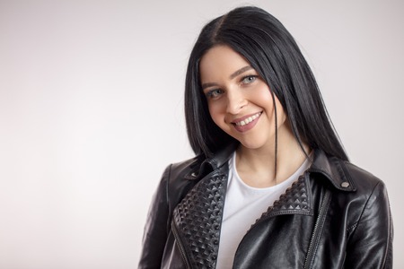 Glamorous young black-haired woman in leather jacket on white backgroundの写真素材