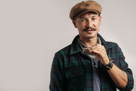 Studio portrait of caucasian moustached man on cap playing harmonica