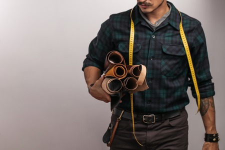 Artisan of leather in creative black hat posing with leather goods in studio.の写真素材