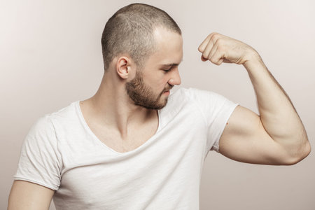 close up side view portrait of a muscular young man showing his biceps