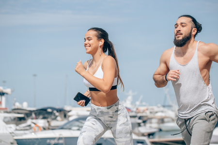 Young sporty couple running over wooden pier at sunsetの写真素材