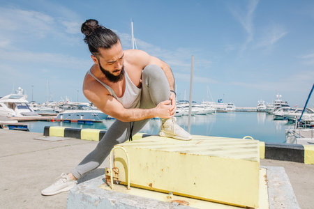 Sports lifestyle. Happy young caucasian bodybuilder stretching on the sea shore.