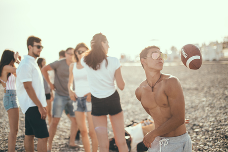 young friends having fun and dancing on beach during sunsetの写真素材