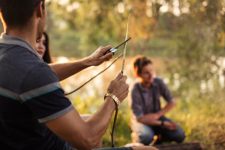 a group of friends preparing sticks to roast sausages