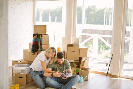 couple with book sitting on bed while moving into new homeの写真素材