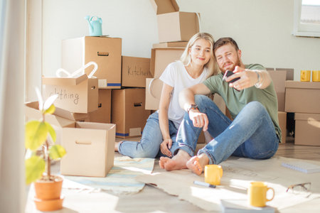 couple moving in new home. Sitting on floor and relaxing after unpacking.Doing selfie with...
