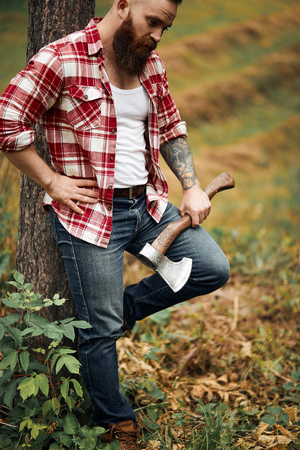 man with red shirt and axe posing near treeの写真素材