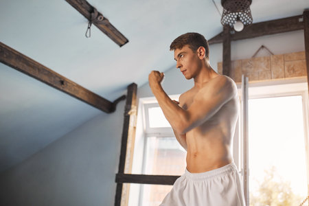Man in white kimono with black belt training karate in gym
