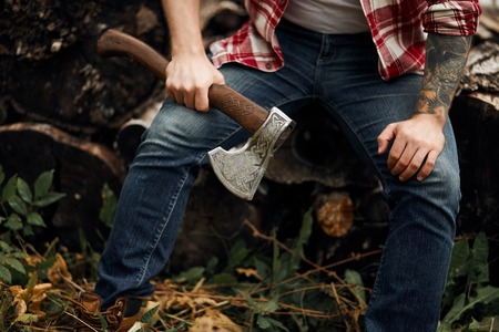 Man sitting on firewoods. Woodcutter with axe resting after workの写真素材