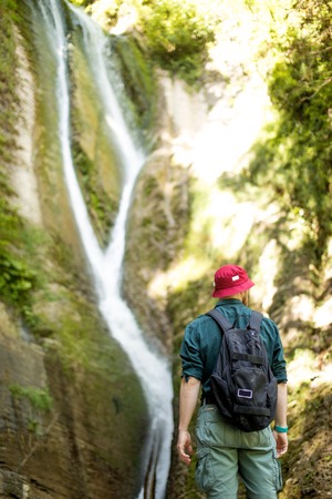 Rear shot of male traveler with lifted hands before waterfall in Icelandの写真素材