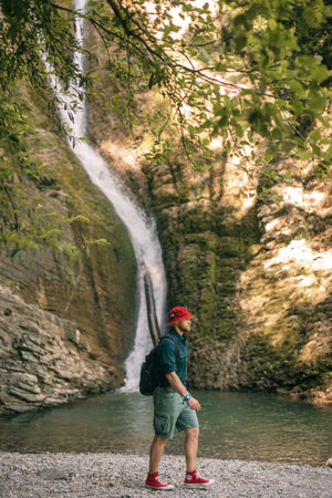 Young tourist camping with backpack near a waterfall in forest.の写真素材