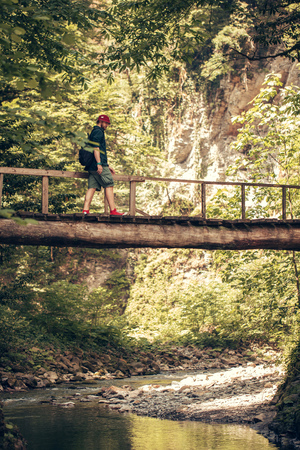 Traveler crosses through hanging bridge in the green summer forest.の写真素材