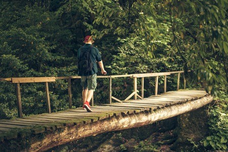 Traveler crosses through hanging bridge in the green summer forest.の写真素材
