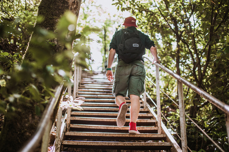 traveler with backpack climbing over wooden bridge in green forestの写真素材
