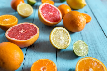 Citrus fruits, whole and sliced on blue wooden background. Selective focusの写真素材