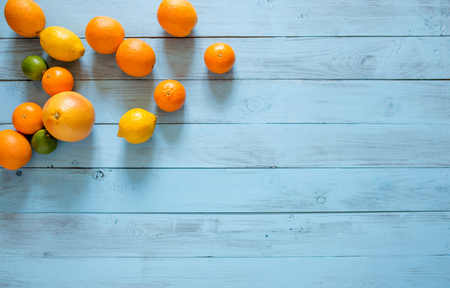 Whole citrus assorty of colourful fruits in the upper corner of blue wooden textured background. Top view. Copy space.の写真素材
