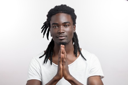 Close up of black man with dreadlocks praying on white backgroundの写真素材