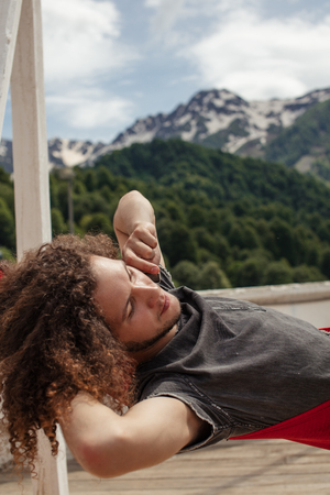 happy man relaxing lying in hammock on top of mountain. Summer vacation travel lifestyle conceptの写真素材