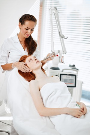 Woman getting laser face treatment in medical center, skin rejuvenation conceptの写真素材
